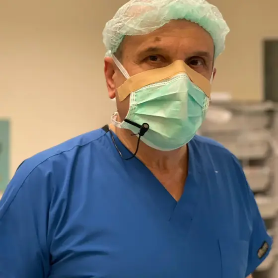 A senior surgeon in blue scrubs in the operating theatre
