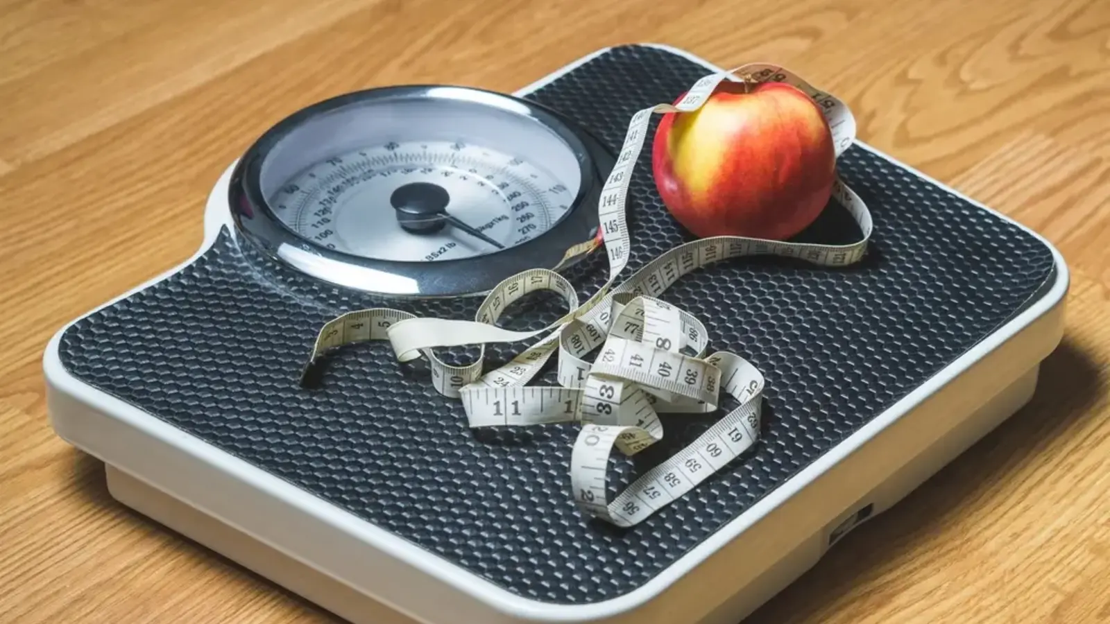 Bathroom scales with an apple and a tape measure on top