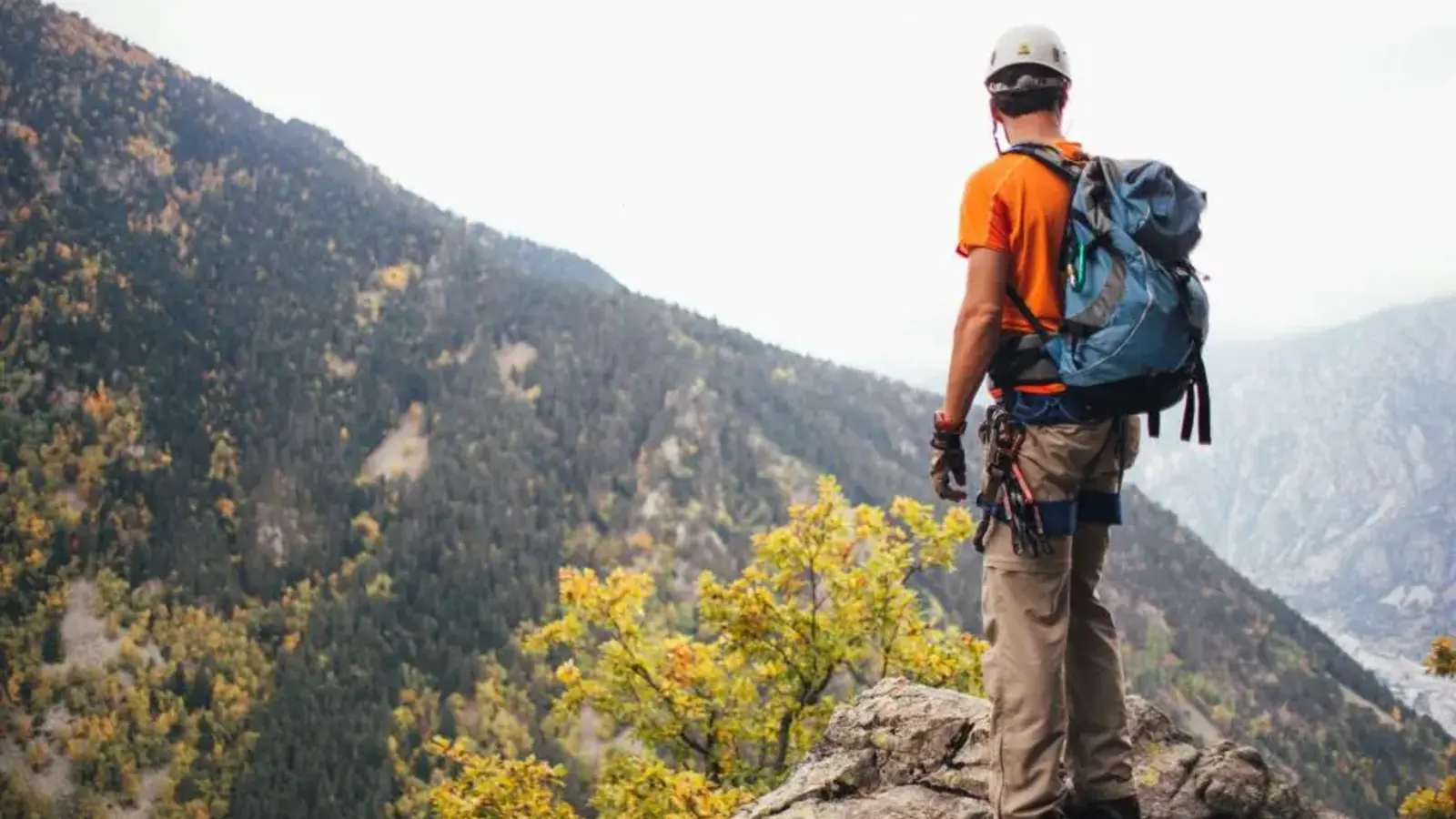 A hiker with a backpack standing on a rocky mountain ledge