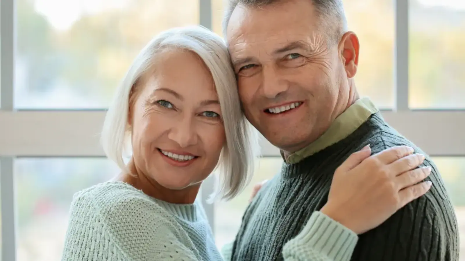 An older couple smiling, cheek to cheek