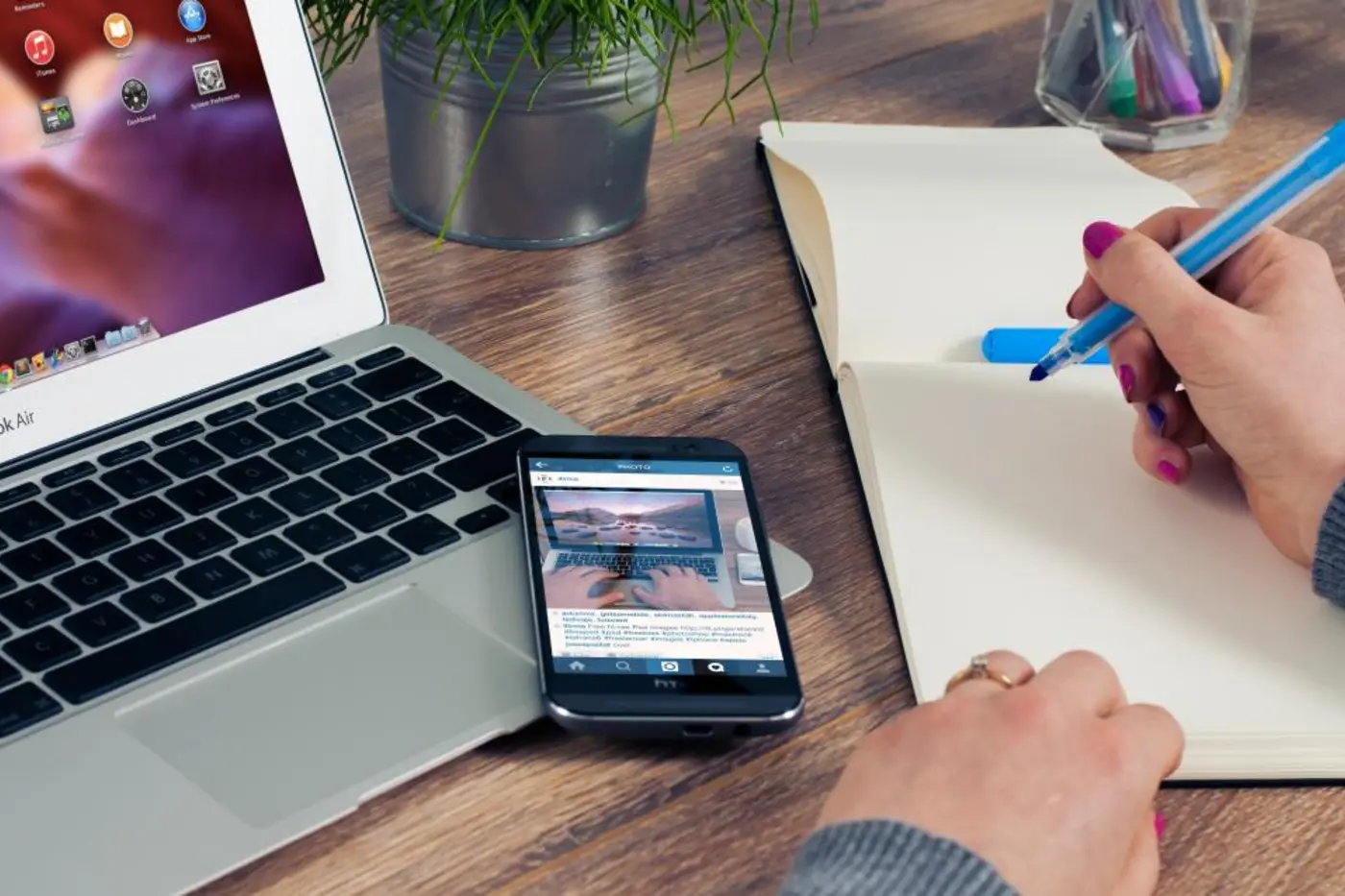 Hands taking notes beside a laptop and phone
