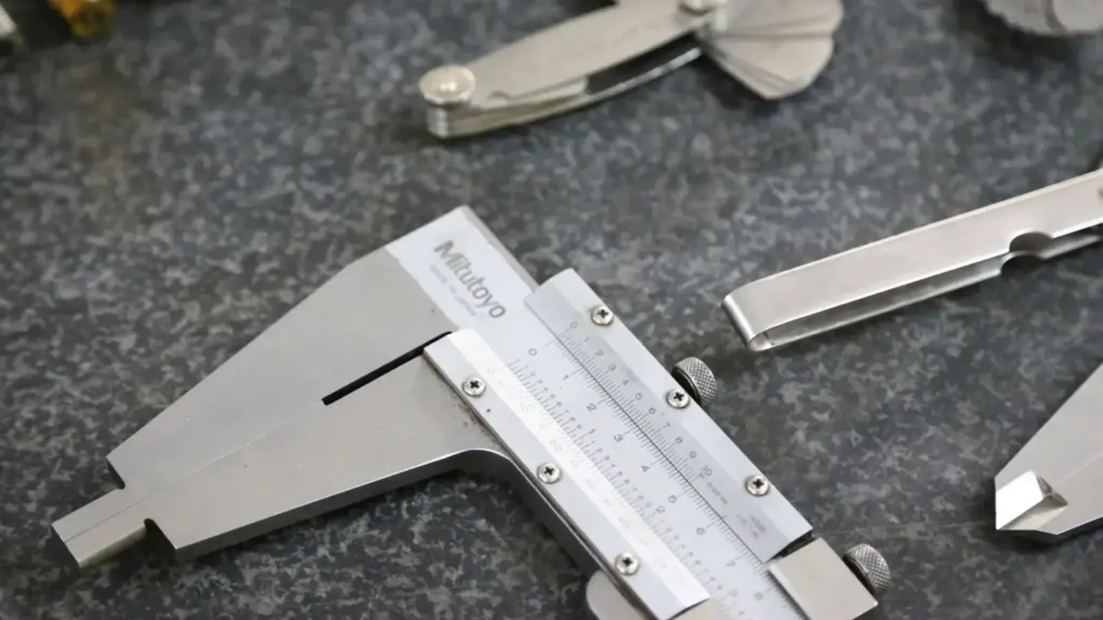 Steel vernier calipers and measuring gauges on a dark granite surface