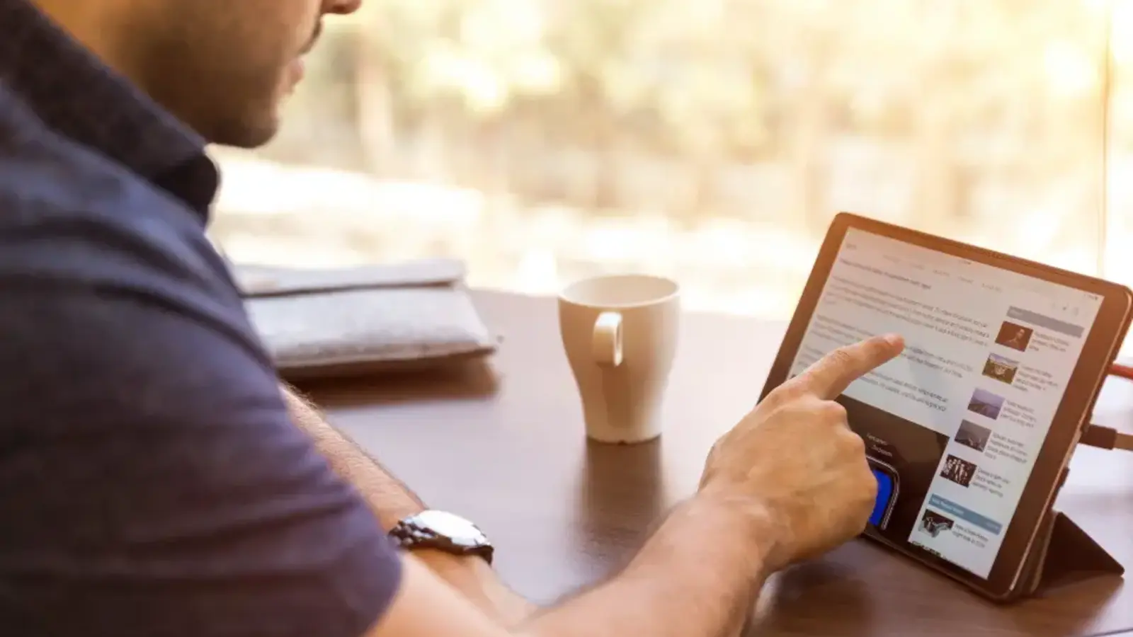 A man reading on a tablet at a table