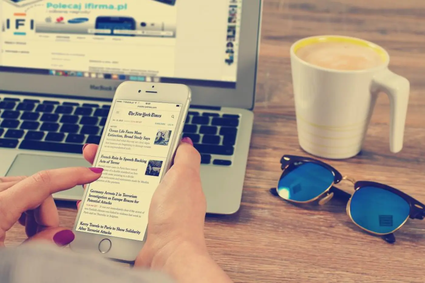 Reading a newsletter on a smartphone beside a laptop