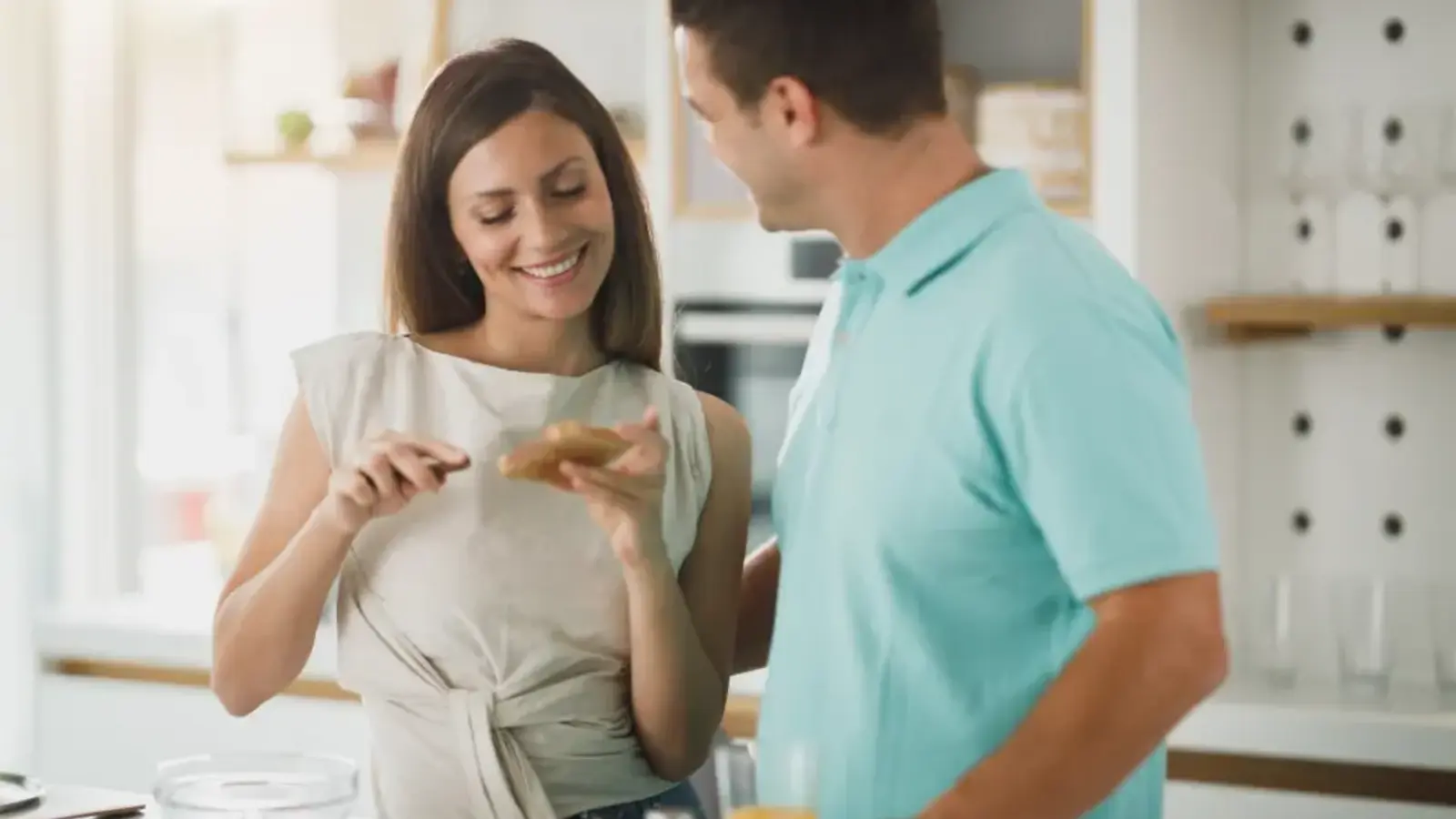A couple talking and laughing while preparing food in a kitchen