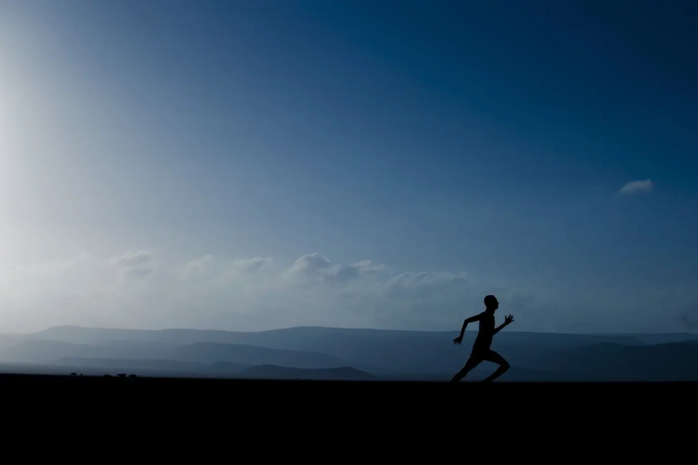 Silhouette of a runner on a hill at dawn