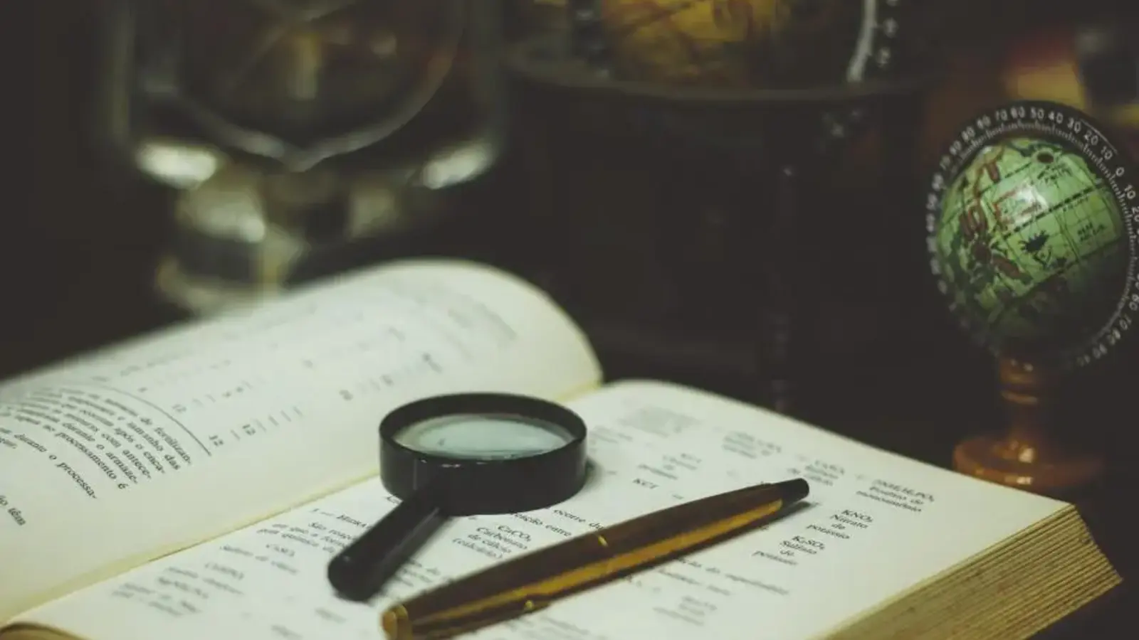A magnifying glass and pen on an open book
