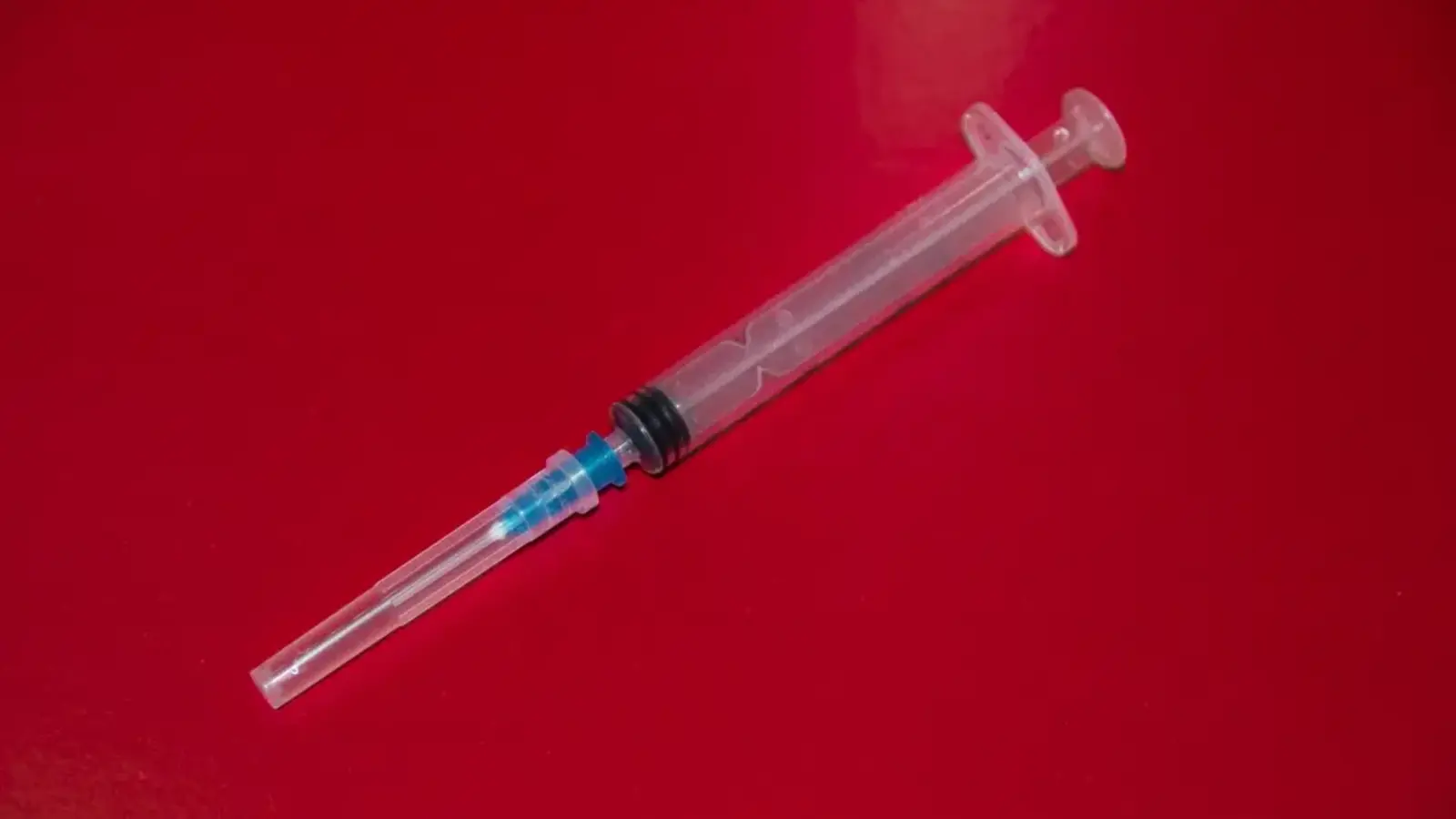 A syringe lying on a red background