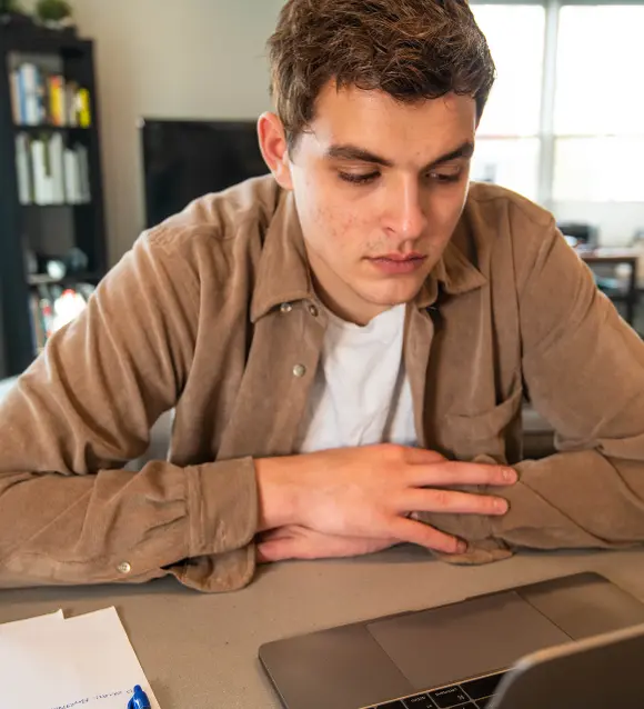 A man sitting at a desk, looking thoughtful
