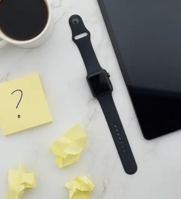 Sticky note with a question mark beside a tablet and a coffee cup