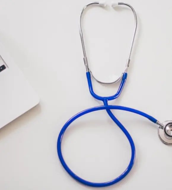 A stethoscope on a desk beside a laptop
